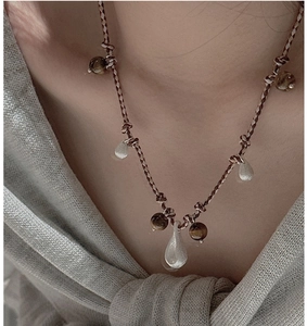 Detail of S925 sterling silver water drop pendant on a hand-woven beaded brown cord