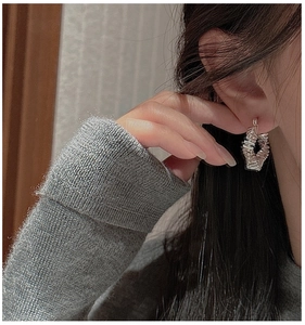 Detailed view of silver hoop earrings with geometric layered texture on model