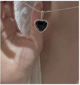 Close-up of S925 silver heart necklace with black enamel inlay worn on a model