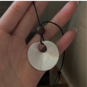 Detail of S925 sterling silver ring pendant with brushed texture and dark wooden bead