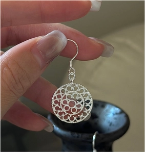 Detailed macro view of S925 sterling silver vintage round hollow floral earrings with ear hooks