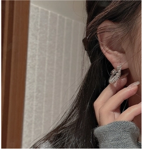 Detail of S925 sterling silver earring with retro wrinkled texture on female model ear