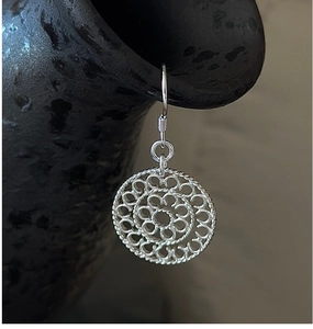 Macro shot of S925 sterling silver filigree drop earring on a vintage ceramic pot edge