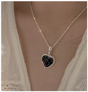 Detail of vintage S925 silver heart necklace with black enamel inlay on a model neck
