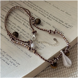 Macro detail of S925 silver teardrop pendant on beaded boho braided necklace