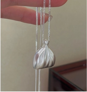 Gros plan du pendentif sac en argent S925 avec finition mate brossée sur chaîne maille