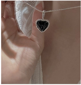 Close-up of a minimalist S925 sterling silver necklace with a black heart pendant
