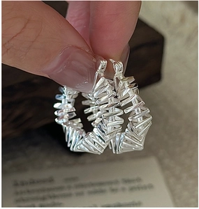Macro shot of silver hoop earrings with a unique geometric twisted texture design
