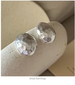 Macro detail of silver S925 sterling silver oval earrings with hand-hammered matte texture
