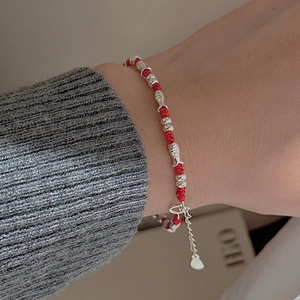Red woven rope bracelet with S925 silver fish charms and beads on model's wrist