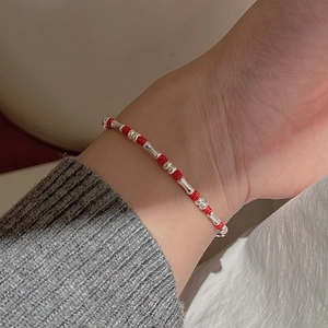 Minimalistisches rotes Kordelarmband mit silbernen Bambusperlen am Handgelenk getragen