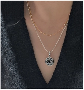 Detail of S925 sterling silver layered necklace with star pendant on model's neck