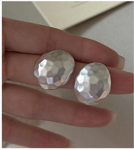 Macro detail of irregular oval S925 silver earrings featuring a hammered matte finish