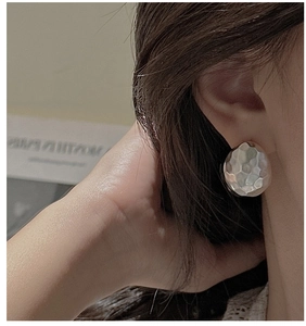 Detail showing the hammered texture on silver stud earrings worn on a model ear