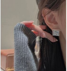 Macro detail of square silver quilted earrings with retro textured metal finish