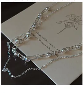 Detail of silver double-layered necklace with long rings and faceted silver beads