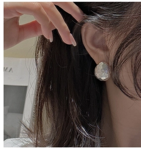 Detail of S925 silver stud earring with hand-hammered texture on the model