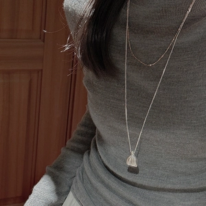 Collier double rang en argent S925 avec pendentif pochette sur un pull en maille