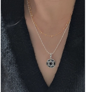 Detail of layered S925 silver hexagram star pendant with gold bead chain on model