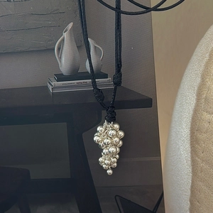 S925 sterling silver grape pendant necklace with a black cord on a rustic wooden table