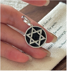 Close-up of S925 sterling silver star pendant with black enamel on a neutral background