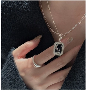 Detail of S925 silver necklace with moon star pendant and wavy minimalist ring on model