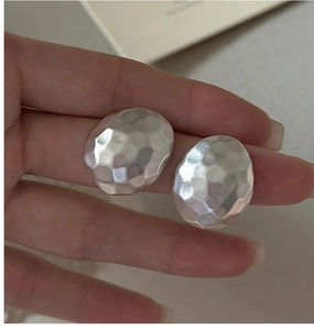Detail of matte S925 sterling silver earrings with textured hammered finish