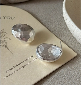 Macro detail of S925 silver stud earrings with unique hammered texture and liquid metal finish