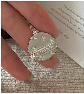 Detail of S925 sterling silver Lucky star pendant held between fingertips