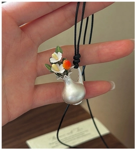 Gros plan détaillé d'un pendentif vase en argent avec fleurs et feuilles faites à la main