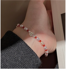 Gros plan d'un bracelet en argent S925 avec perles irrégulières et agate rouge au poignet