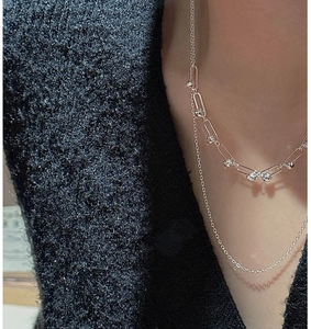 Detail of layered S925 sterling silver necklace with beads on grey knit background