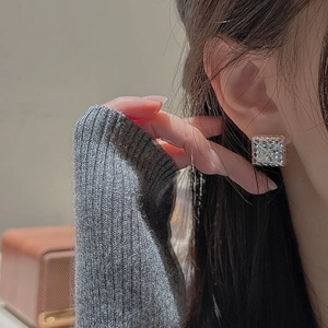 Elegant square silver stud earrings with diamond-like texture worn by a model