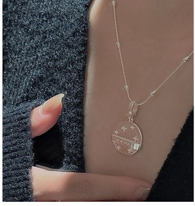 Close-up of S925 silver coin pendant with LUCKY engraving and star motifs on a thin chain