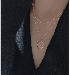 Detail of layered S925 silver necklace with Lucky embossed star pendant on tweed background