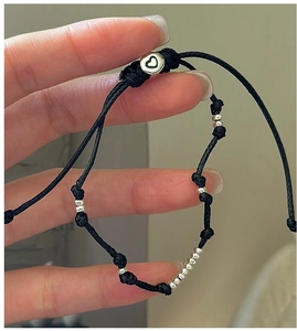 Nahaufnahme vom schwarzen geflochtenen Armband mit Silberperlen und Herzanhänger