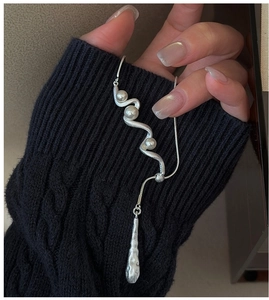Detail of wavy S925 silver necklace with pearls and matte pendant on black knit