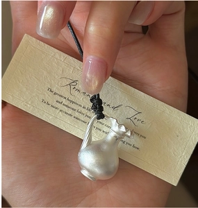 Gros plan sur le pendentif vase en argent S925 mat tenu par un cordon noir minimaliste