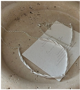 Macro detail of S925 sterling silver knotted rope necklace on artistic display tray