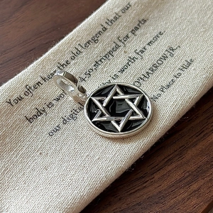 S925 sterling silver hexagram pendant with black enamel on a rustic wood background