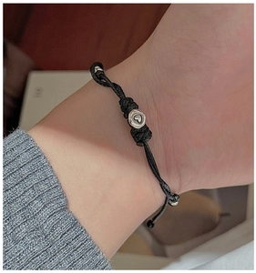 Detailaufnahme des minimalistischen schwarzen Textilarmbands mit einem Herzanhänger in Silber