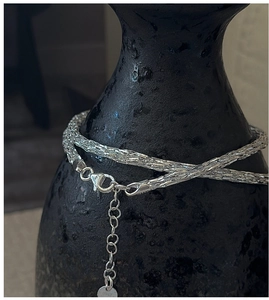 Macro shot of S925 sterling silver chain with lobster clasp and Italy tag on black vase