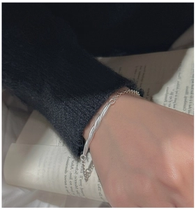 Detail view of S925 sterling silver twisted tube bracelet on wrist with elegant lifestyle setting