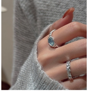 Close-up of S925 silver rings with oval light blue gemstone and textured band on hand
