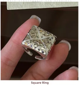 Macro detail of a silver square signet ring with geometric facets and cross design