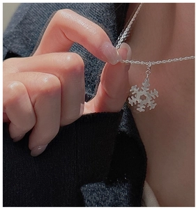 Dettaglio di una collana con ciondolo a fiocco di neve in argento S925 su un maglione scuro