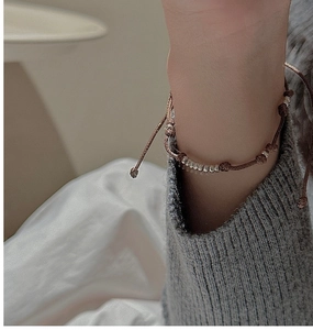 Detail eines handgewebten braunen Seilarmbands mit polierten Silberperlen am Handgelenk