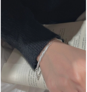 Macro detail of S925 sterling silver twisted bar bracelet on a model wearing black