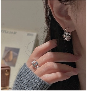 Detail of silver S925 liquid metal earrings and matching ring on model in warm light