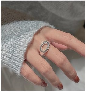 Close-up of a minimalist hollow oval silver ring on finger with soft lighting texture